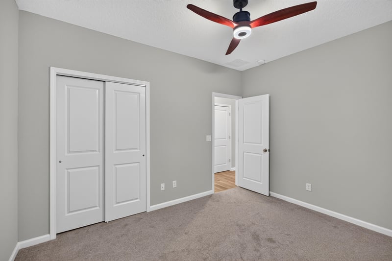 Carpeted bedroom with closet doors and ceiling fan at 75875 Saffron Ln, Yulee, FL 32097