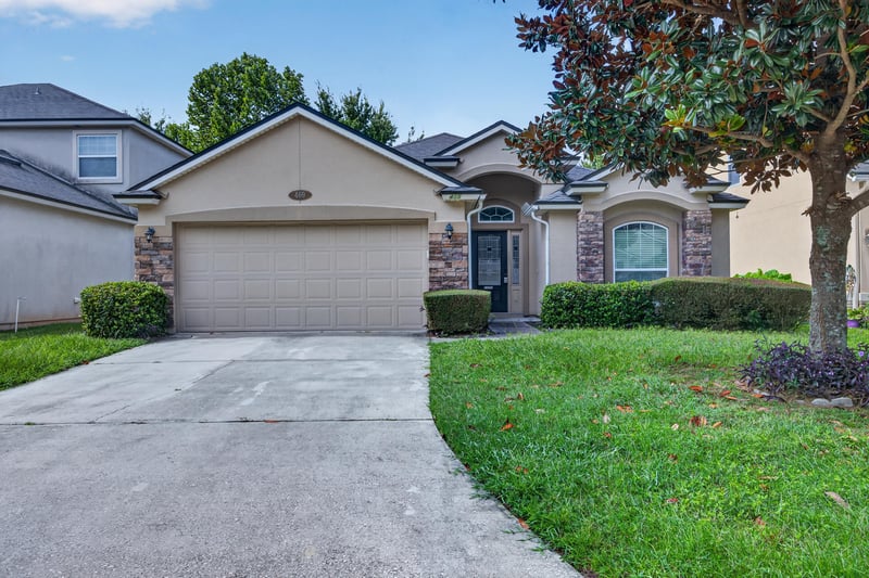 Front exterior with two-car garage and shade tree at 469 Glendale Ln, Orange Park, FL