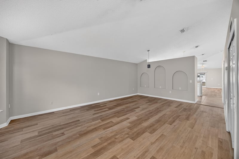 Empty room with wood-look flooring and arched doorway at 1845 Saga Ct, Middleburg, FL