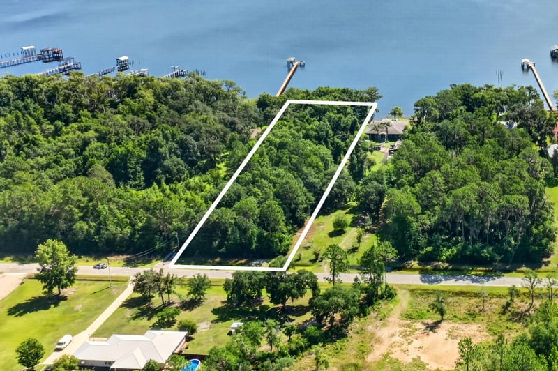 Aerial view of the outlined lot near neighboring homes and a pool at 110 River Shores Rd, Palatka, FL 32043