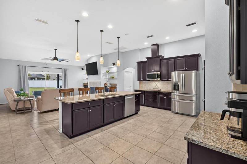 Kitchen island with bar seating and living room beyond at 538 Porta Rosa Circle, St. Augustine, FL 32092