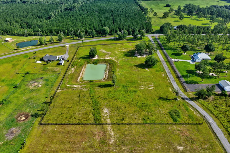 Aerial view of a pond and tree line bordering open rural land at 7500 Lucky Seven Rnch Rd, Macclenny, FL