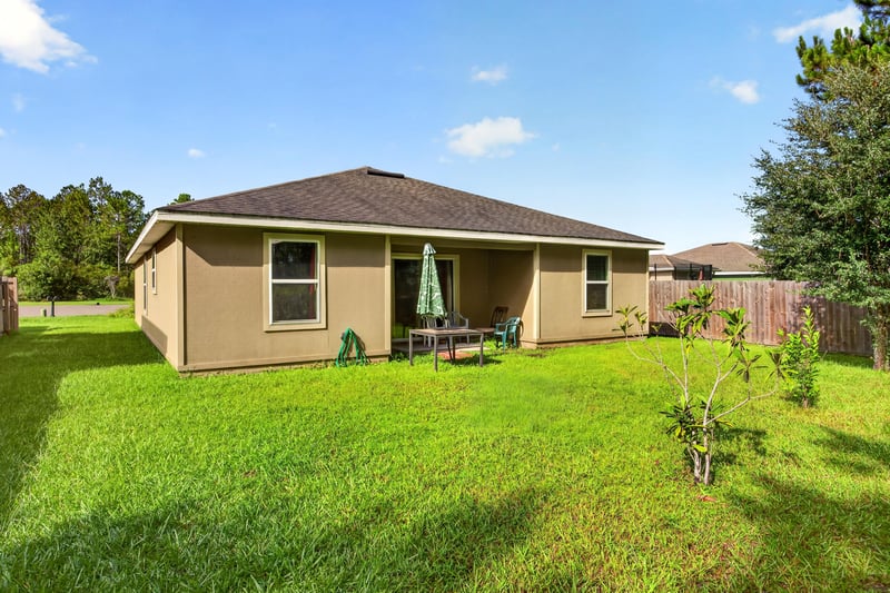 Backyard with covered patio and open lawn at 518 Matecumbe Ct, Macclenny, FL