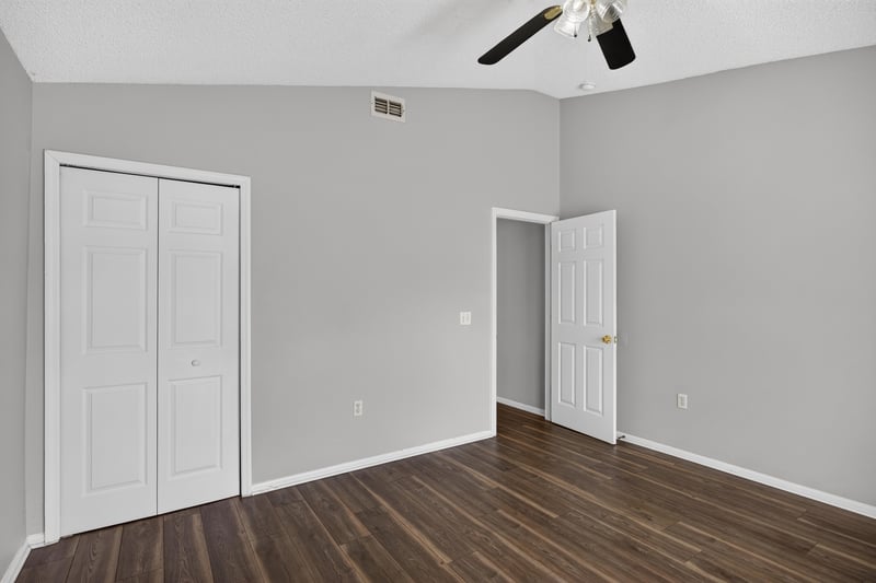 Bedroom with wood-look flooring and two closet doors at 7329 Lawn Tennis Ln, Jacksonville, FL