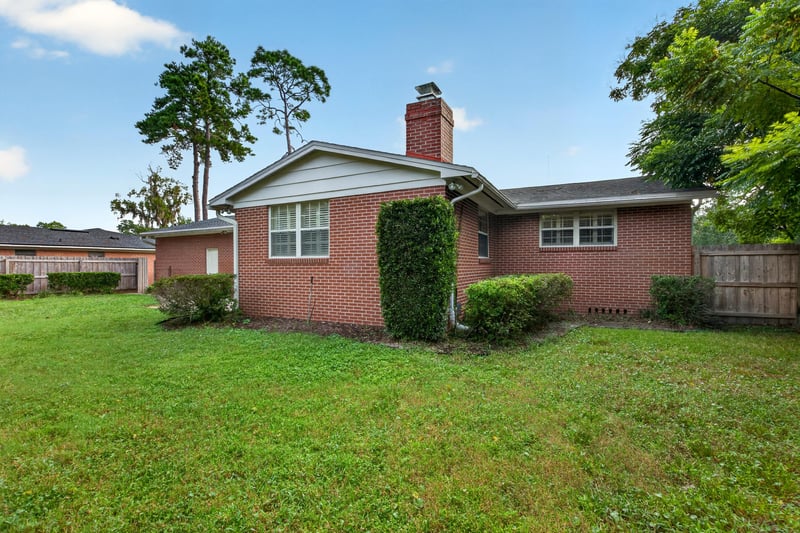 Backyard view of brick home with chimney and shrubs at 1834 Memory Ln, Jacksonville, FL