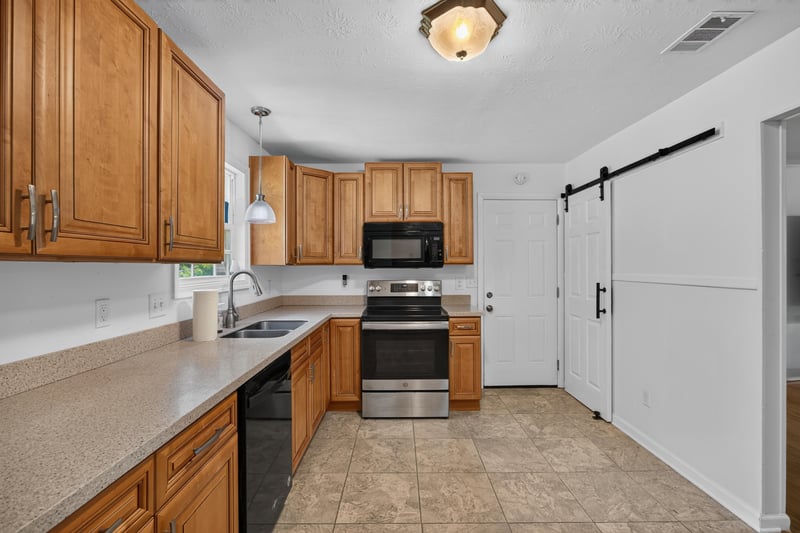 Kitchen with barn door and black appliances at 1847 Grove Park Dr, Orange Park, FL