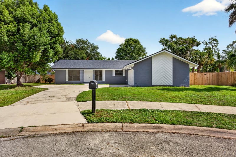 Front exterior with blue siding, white garage doors, and landscaped lawn at 4117 Wilcrest Ct, Jacksonville, FL 32277