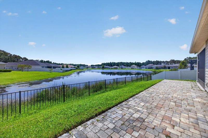 Paver patio with pond view and fenced yard at 855 Flach Dr, St. Johns, FL
