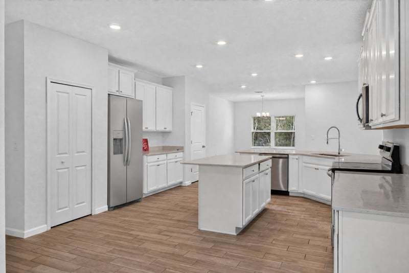 Kitchen with white cabinets and island seating, virtually staged at 9905 Ansley Lake Dr, Jacksonville, FL
