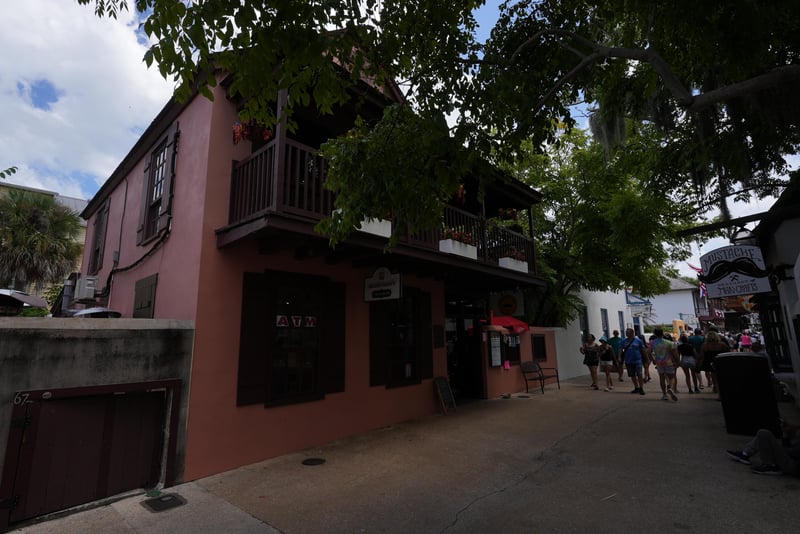 Close view of the pink stucco corner with wrought-iron balcony above the sidewalk at 29 Cuna St, St. Augustine, FL 32084