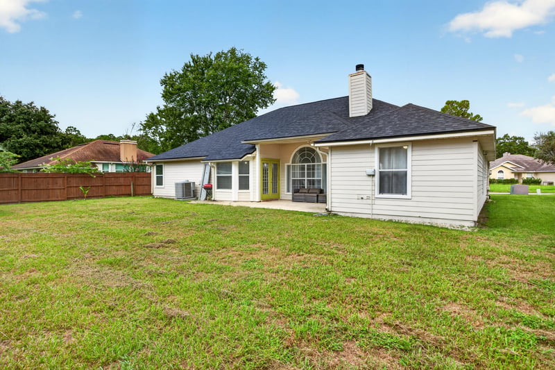 Backyard exterior with chimney and fenced yard at 8921 Needlepoint Pl, Jacksonville, FL 32244