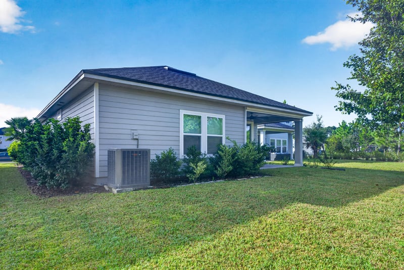 Back exterior with covered patio and grass yard at 75875 Saffron Ln, Yulee, FL 32097