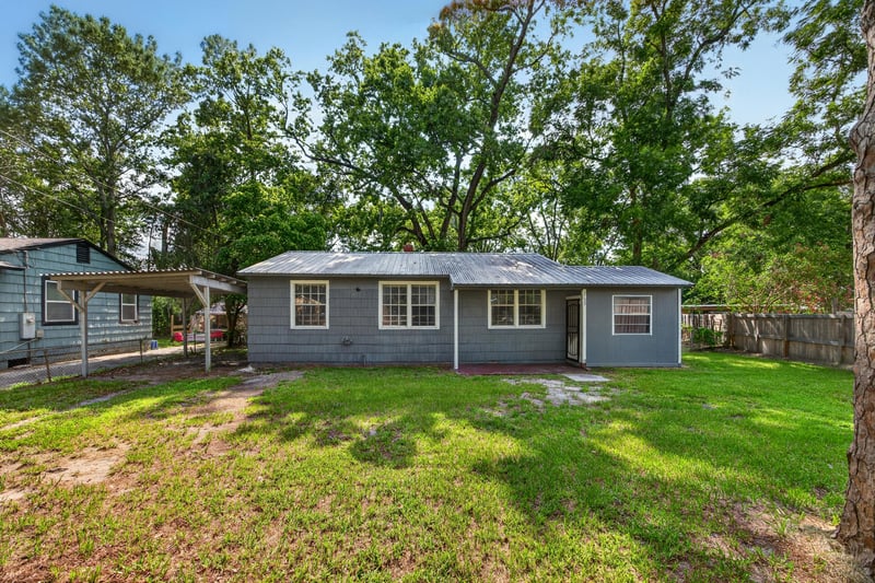 Front exterior with metal roof and mature trees at 2132 Allandale Cir W, Jacksonville, FL