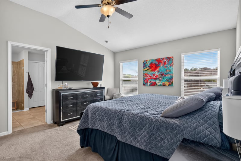 Primary bedroom with wall-mounted TV and window at 589 Seville Pkwy, St. Augustine, FL
