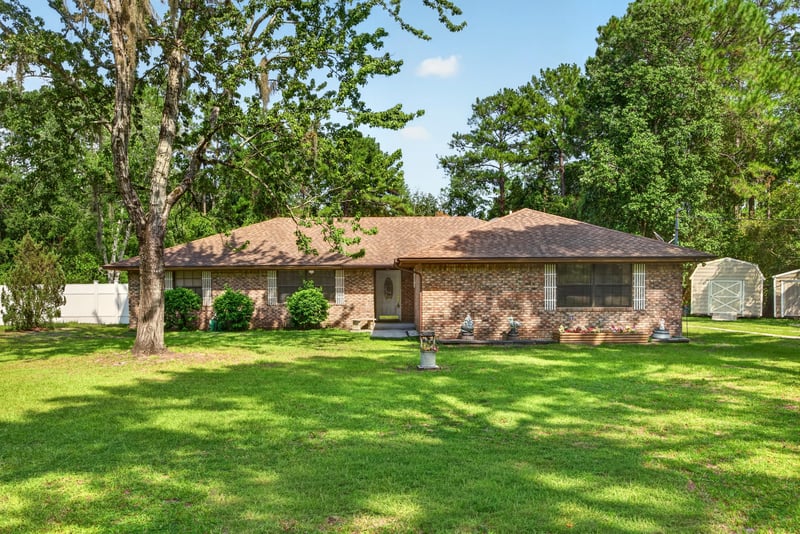 Front exterior of brick ranch home with mature trees at 2435 Range Line Rd, Middleburg, FL
