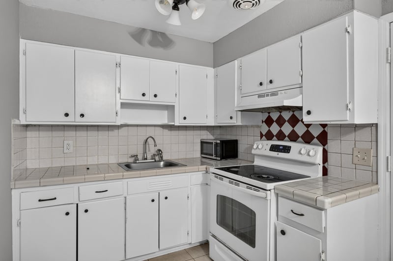 Kitchen with white cabinets, microwave and range at 4030 Leonard Cir W, Jacksonville, FL 32209