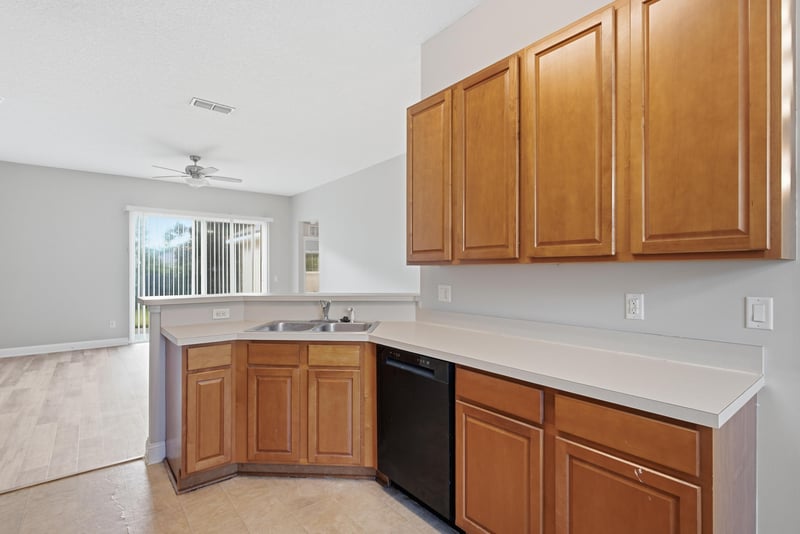 Kitchen sink area with wood cabinets and black dishwasher at 14187 Big Spring St, Jacksonville, FL 32258