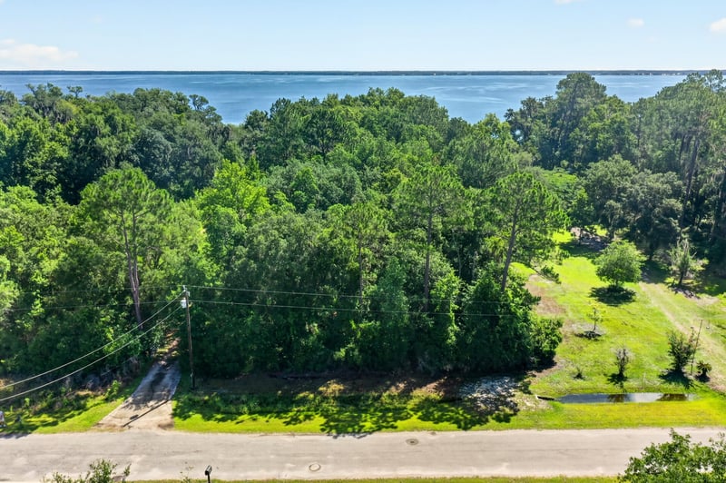 Aerial view of the wooded lot bordering the road and a small pond at 110 River Shores Rd, Palatka, FL 32043