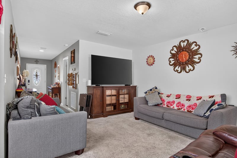 Second living area with gray sofa and mounted TV at 518 Matecumbe Ct, Macclenny, FL