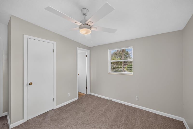 Carpeted bedroom with door and window at 87 Saratoga Cir S, Atlantic Beach, FL