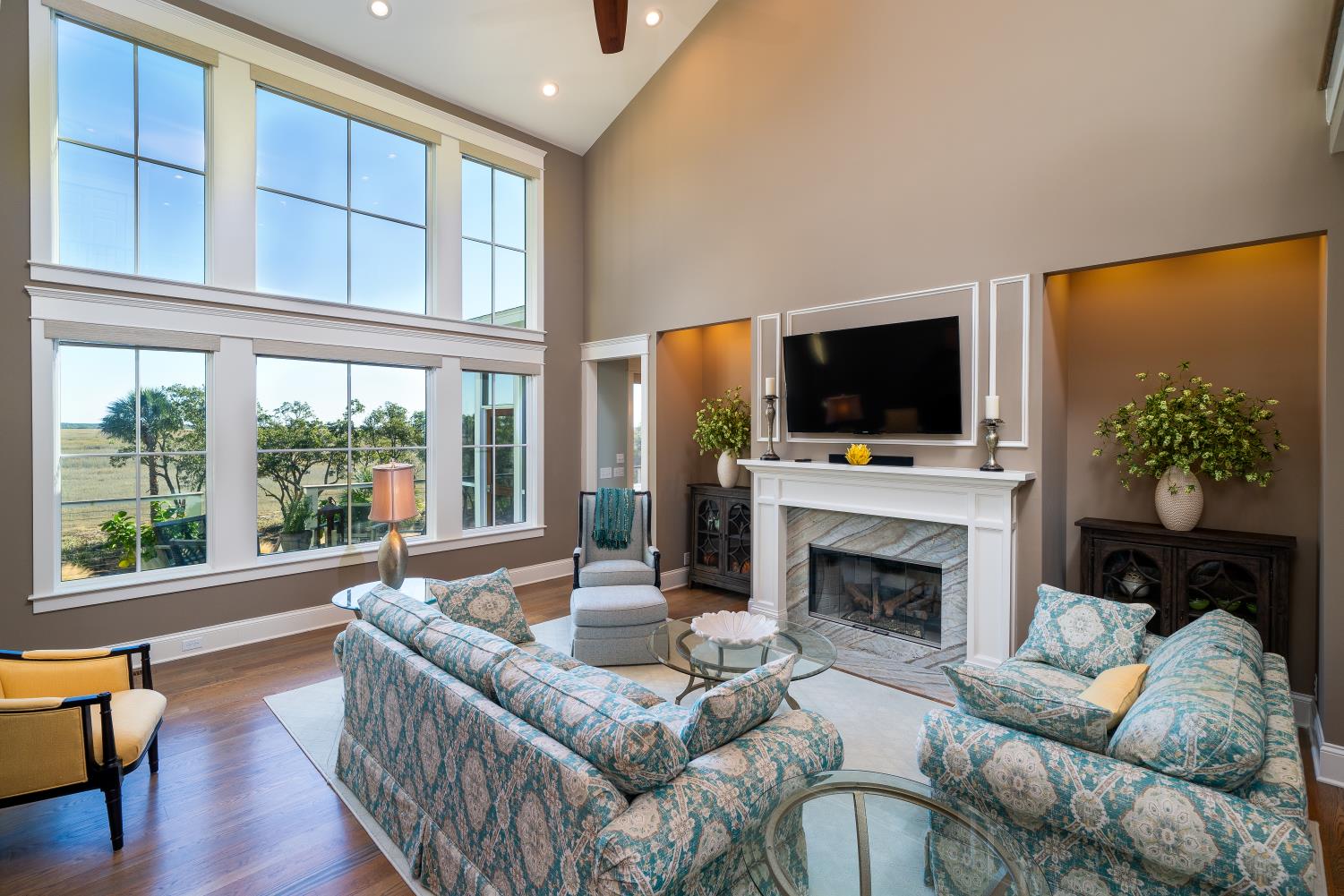 Two story living room windows with blue sky over the marsh
