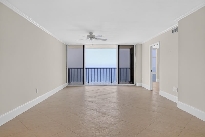 Living room with ceiling fan and ocean view through sliders at 1301 1st St S