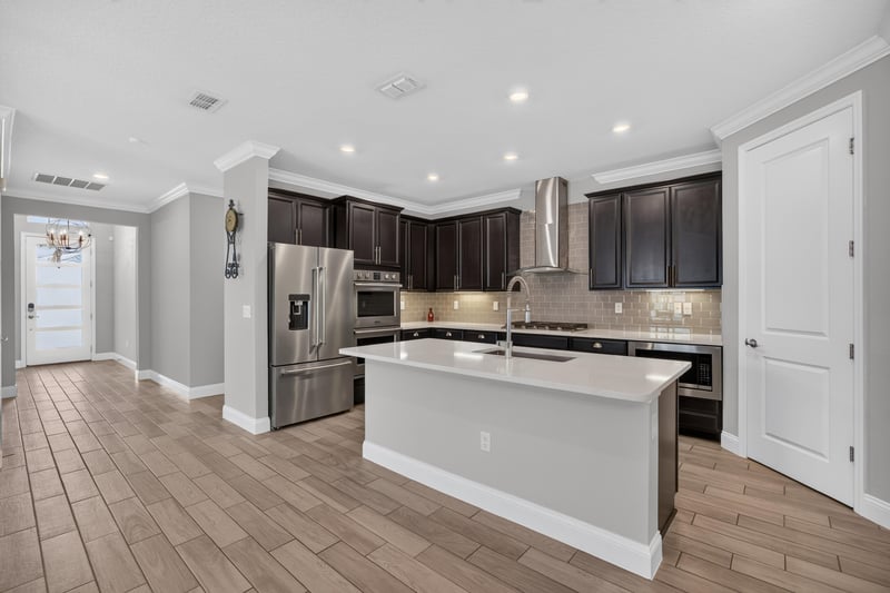 Kitchen with dark cabinets, white quartz island and stainless appliances at 91 Tilloo Ct, St. Johns, FL