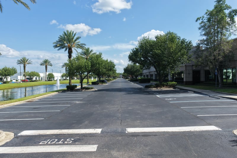 Street view lined with palm trees leading into the office park at 10550 Deerwood Park Blvd, Jacksonville, FL 32256