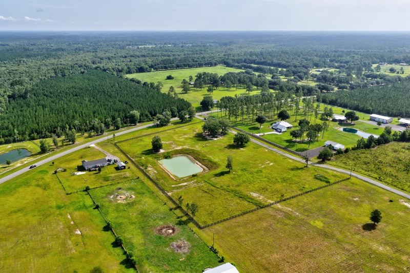 Wide aerial view of open pasture, a pond and scattered homes at 7500 Lucky Seven Rnch Rd, Macclenny, FL
