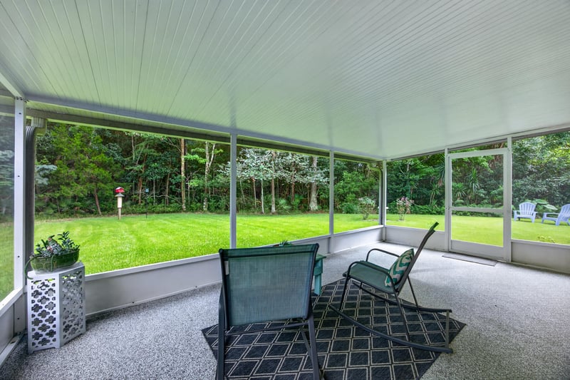 Screened porch with seating area and wood floors at 13514 Las Brisas Way N, Jacksonville, FL