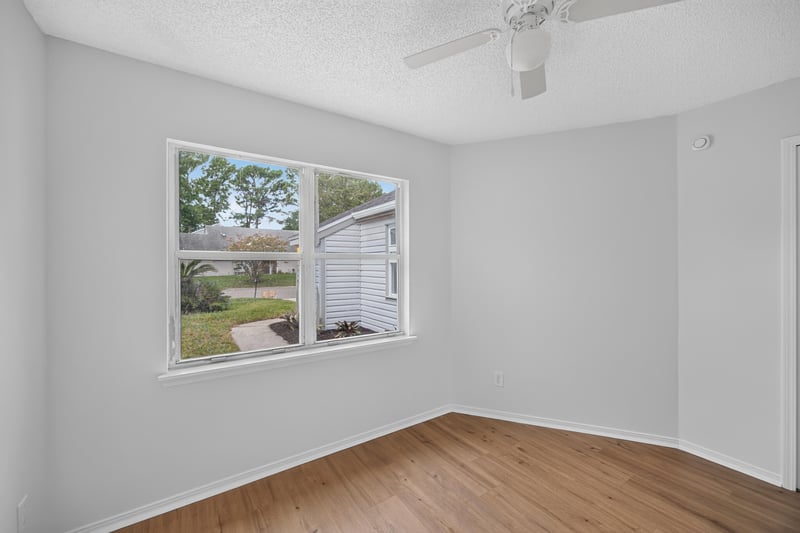 Bedroom with two windows and wood floors at 8047 Mactavish Way E, Jacksonville, FL 32244