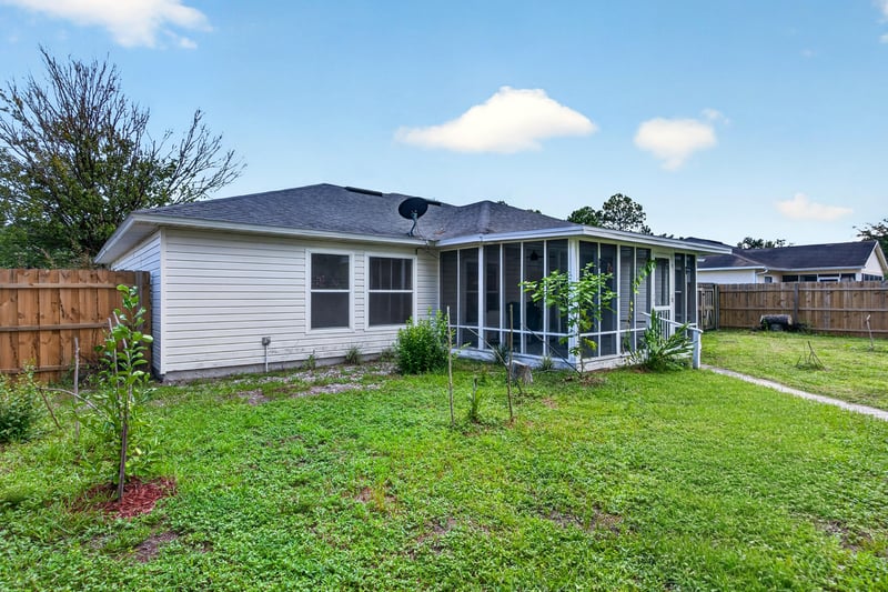 Backyard view of screened porch and lawn at 9691 Nelson Forks Dr, Jacksonville, FL 32222