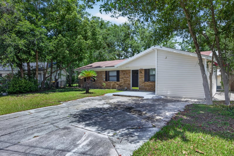 Front exterior from across the lawn showing driveway and covered entry at 7453 Jade Dr N, Jacksonville, FL 32210