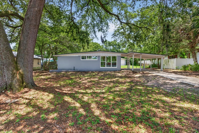 Front exterior with carport and shaded yard at 1928 Montmarte Dr, Jacksonville, FL 32210