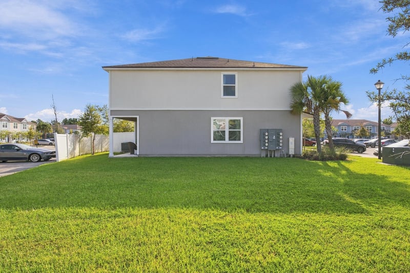Rear exterior view with grass yard and parking at 8359 Zenith Cir, Jacksonville, FL 32256