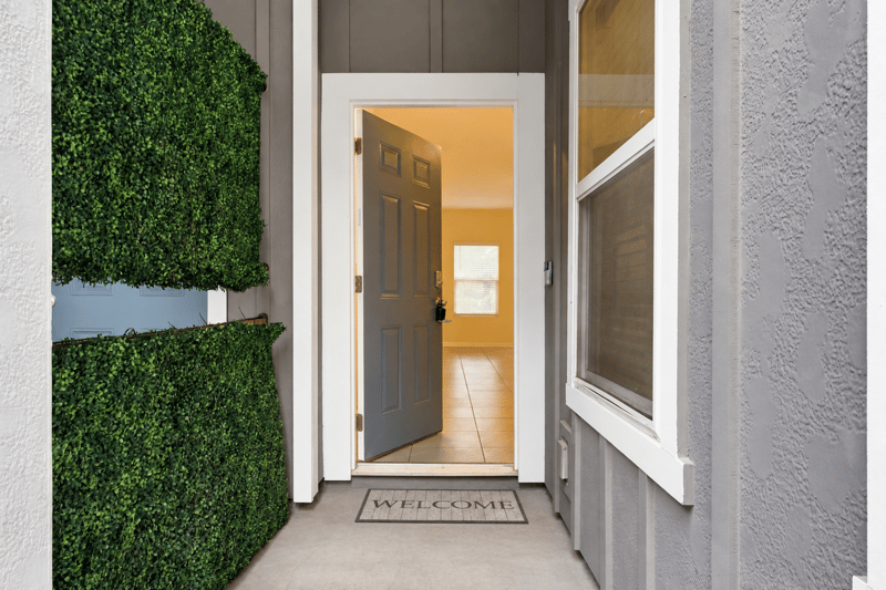 Open front door with welcome mat and greenery accent at 9555 Star Dr, Jacksonville, FL 32256