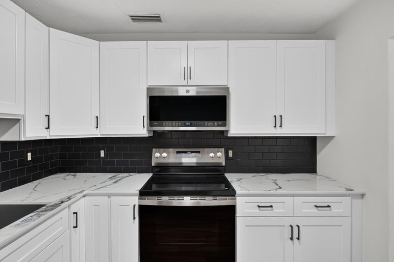 Kitchen with white cabinets and black backsplash at 4039 Habana Ave, Jacksonville, FL