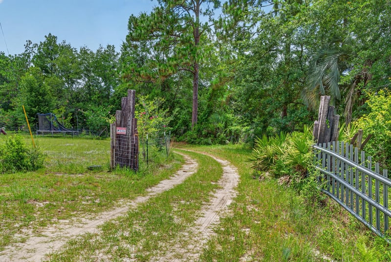 Dirt driveway path through trees and fence line at 4890 McAllister Rd, Middleburg, FL 32068