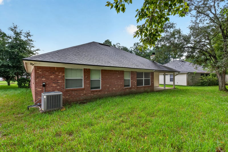 Rear exterior with brick facade and AC unit at 11669 Collins Creek Dr, Jacksonville, FL 32258