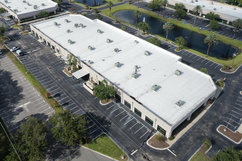 Aerial view of a roofline with pond, palm trees and parked cars at 10550 Deerwood Park Blvd, Jacksonville, FL 32256