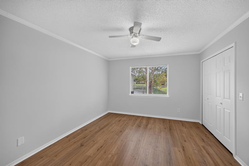 Empty bedroom with window and wood floors at 8047 Mactavish Way E, Jacksonville, FL 32244