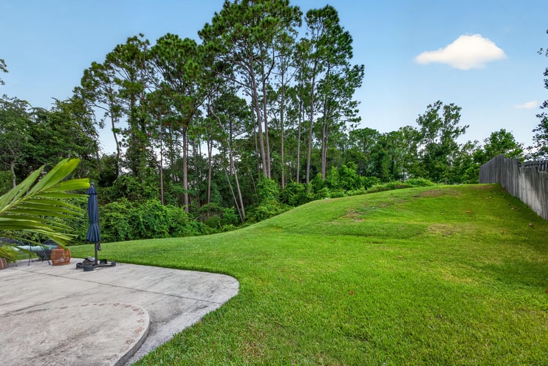 Backyard lawn with trees along the property line at 1820 Burgess Hill Dr E, Jacksonville, FL