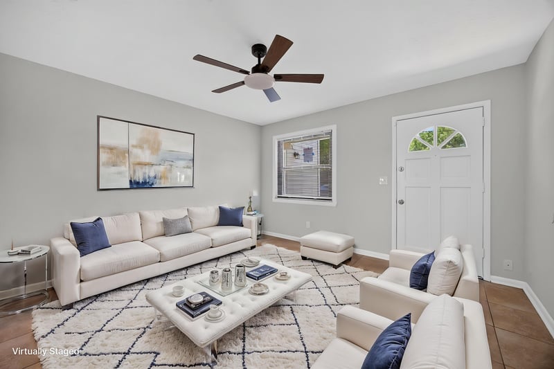 Virtually staged living room with sofa, area rug and ceiling fan at 7453 Jade Dr N, Jacksonville, FL 32210