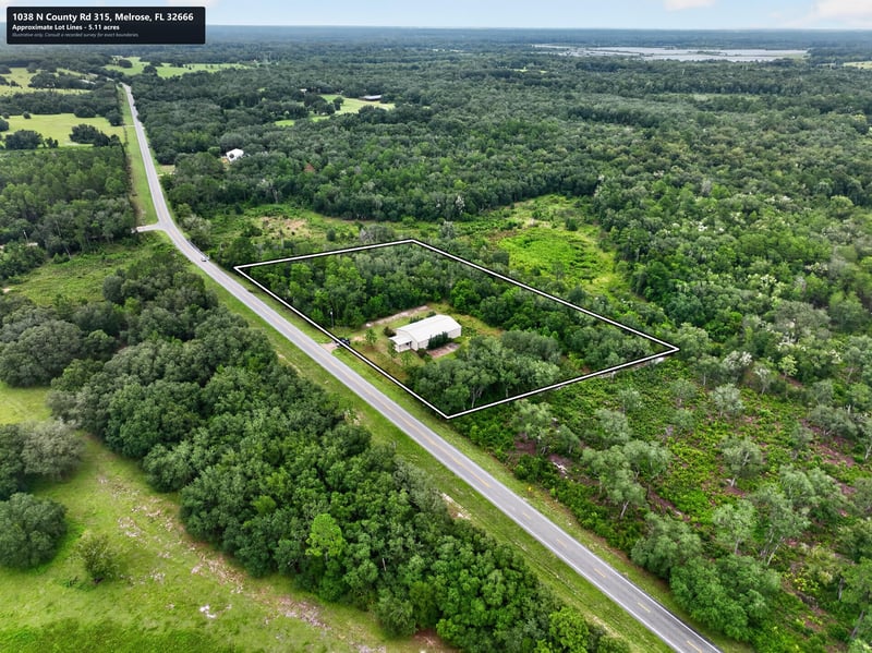Drone aerial along tree-lined road leading to the building at 1038 County Rd 315, Melrose