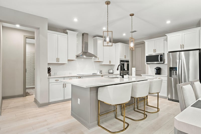Kitchen island with gold-finished stools and pendant lights at 3921 Spyglass Hill Ln