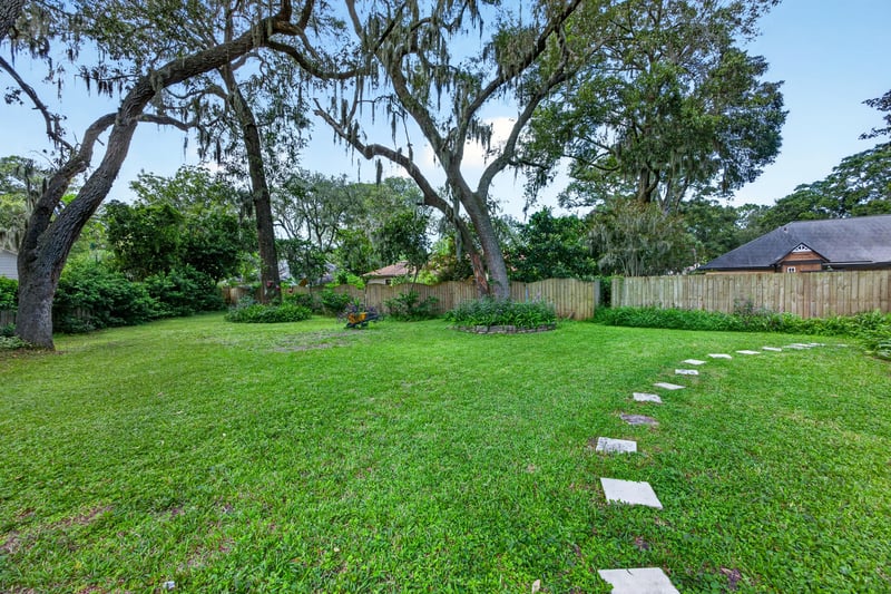 Backyard lawn with stepping stones and oak trees at 1346 Gately Ct, Jacksonville, FL 32225