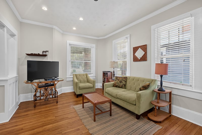 Living room with green sofa, TV and area rug at 1555 Belmonte Ave, Jacksonville, FL 32207