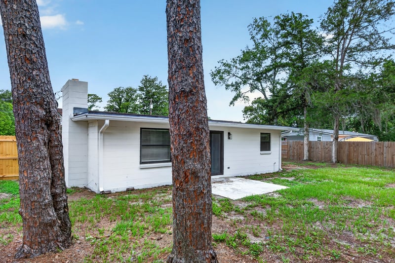 Backyard exterior with chimney and wooded lot at 184 Draco St, Orange Park, FL 32073