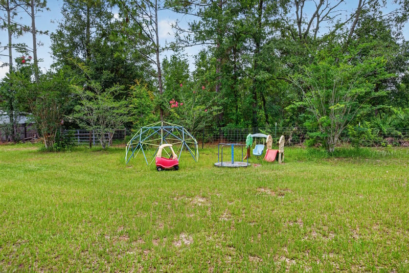 Backyard playground with spring rider and swings at 4890 McAllister Rd, Middleburg, FL 32068
