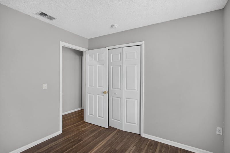 Bedroom with wood-look flooring and closet doors at 7329 Lawn Tennis Ln, Jacksonville, FL